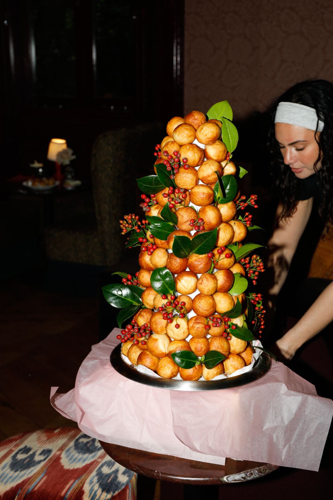 Jemma Harrison setting down a croquembouche tower dressed with berries and leaves